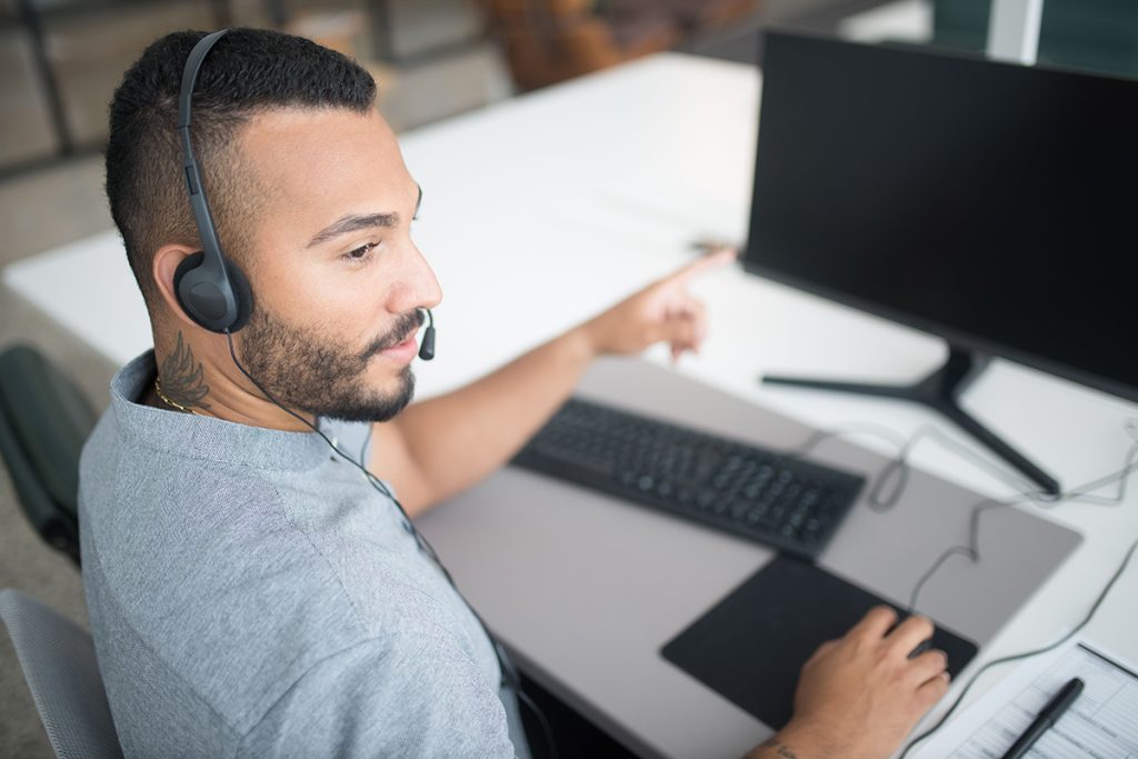 Professional call center agent wearing a headset providing customer support while working at a desktop computer.