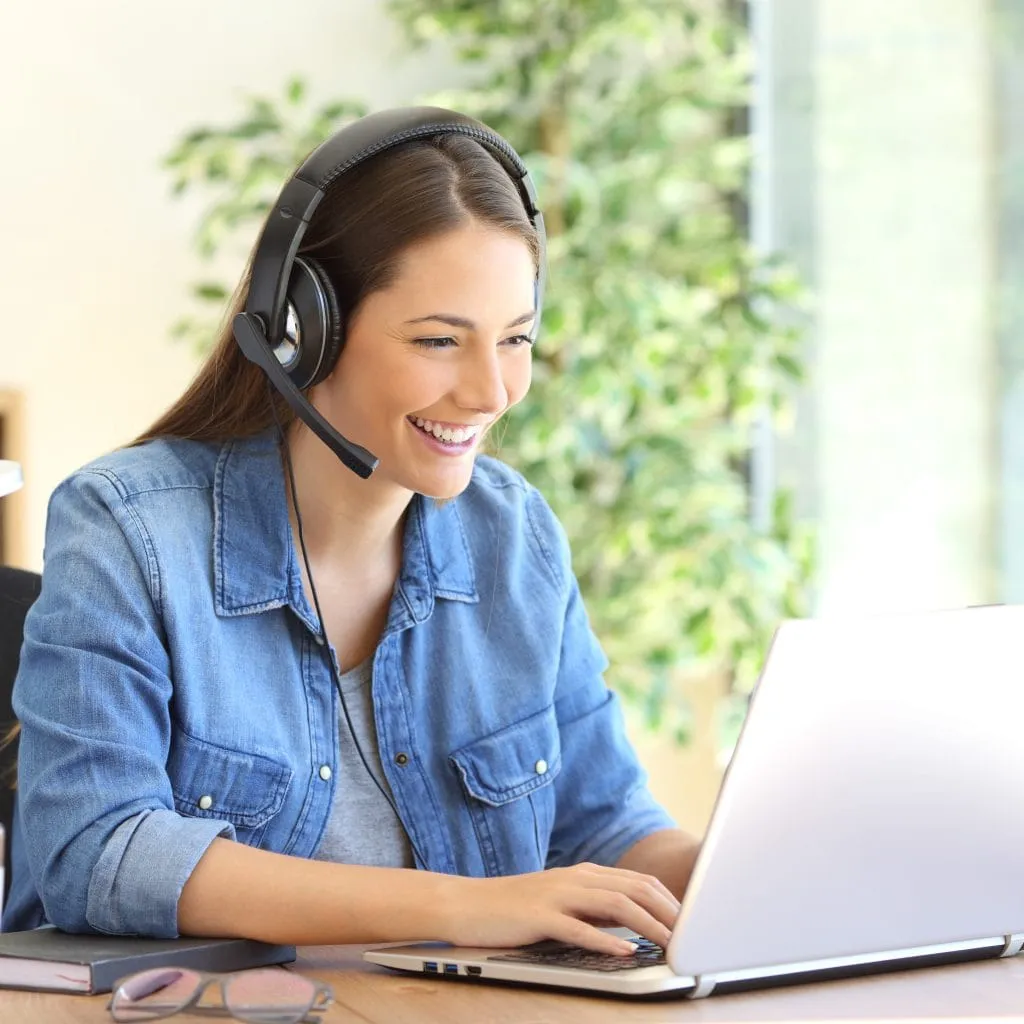 Woman assisting a customer while wearing a headset and using a laptop